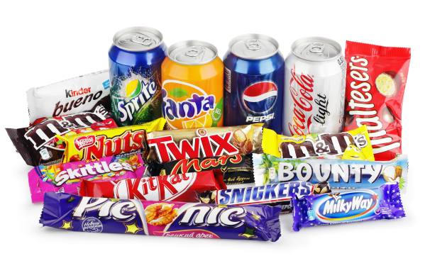 Large collection of junk food isolated on white. Includes Coca Cola, Pepsi, Fanta, Sprite, Skittles, Snickers, Kit Kat, Twix, Bounty, Mars, Milky Way, Picnic, Nuts, Kinder Bueno, Maltesers, M&M's.