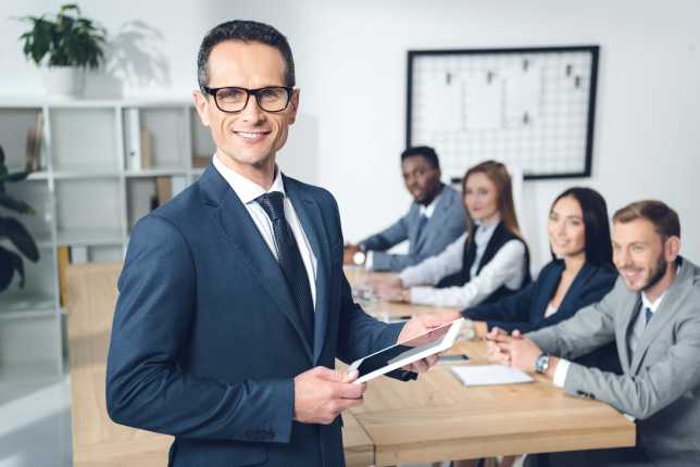 Business man smiling with colleagues behind