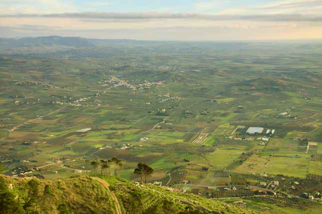 Picturesque view to the fields in rural area and hills with tree